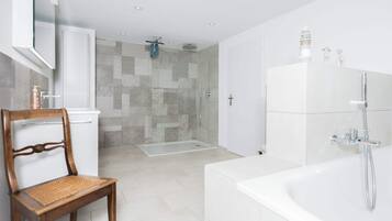 A modern bathroom with a bathtub, shower, and a glass-enclosed shower area.