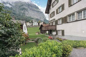 A traditional chalet with a mountain backdrop, a well-maintained garden, and a clear view of the surrounding landscape.