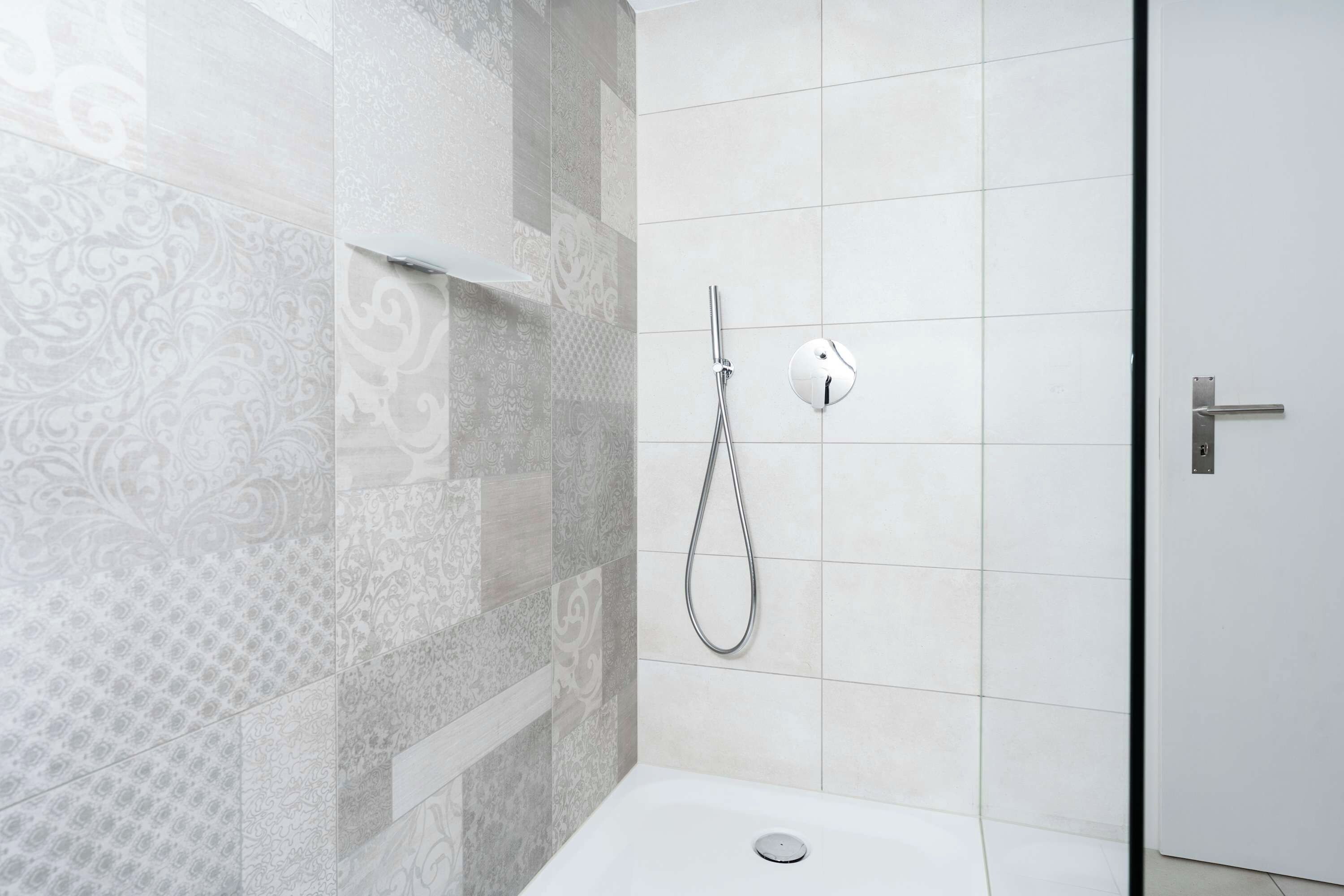Ein Duschbereich mit Handbrause und Armaturen an der Wand.