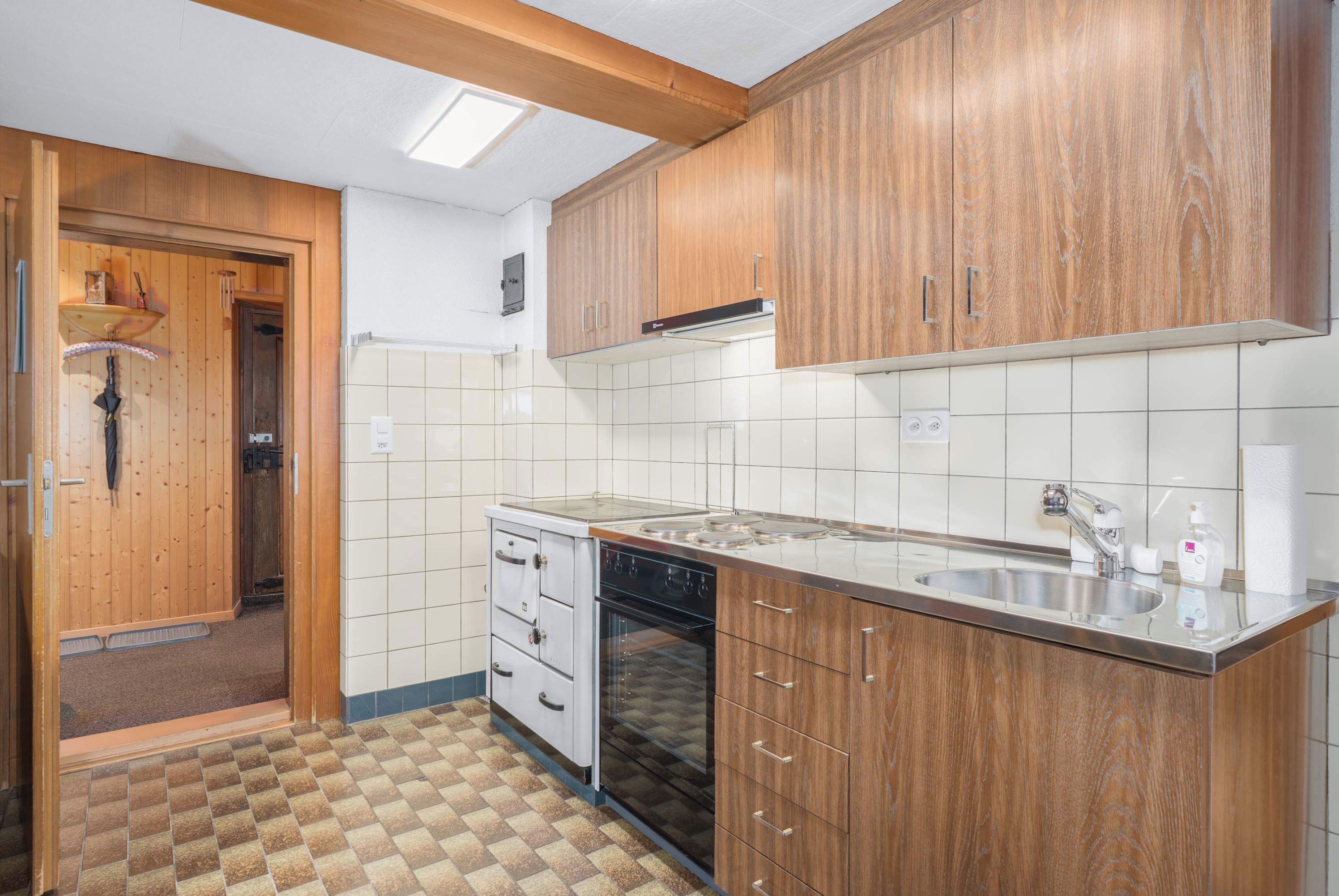 Una cucina compatta con mobili in legno, forno integrato e lavello.
