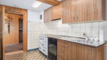 Une cuisine de taille réduite, dotée de meubles de rangement en bois, d’un four encastré et d’un évier.