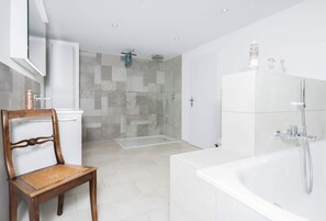 Un baño moderno con bañera, ducha y zona de ducha con mampara de vidrio.