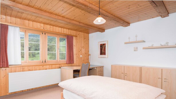 A room with a bed, a desk, a chair, a radiator, and a window with curtains. - Twin Room near Glarus, Desk & Parking (Glarus Süd)