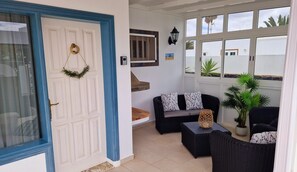 A room with a white door, a black wicker sofa, a small table, and a potted plant. - Villa Jude with private heated pool (Puerto del Carmen)
