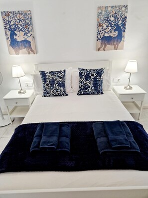 A hotel room with a bed, two nightstands, two lamps, two leopard print pillows, a dark blue blanket, and two wall art pieces. - Villa Jude with private heated pool (Puerto del Carmen)