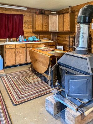 A rustic kitchen with wooden cabinets, a stove, and a dining table.