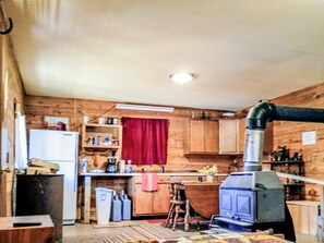 A compact kitchen with wooden walls, a refrigerator, a stove, and a sink.