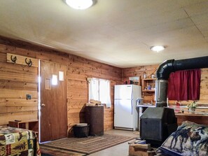 A cabin interior with a wooden interior, a refrigerator, a stove, and a door with a window.