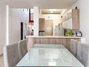A modern kitchen with a glass dining table, wooden cabinets, and a built-in microwave. - Spacious 4-bedroom apartment in soothing Cartagena de Indias with AC (Cartagena de Indias)
