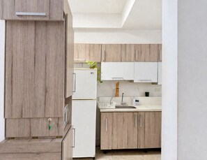 Eine moderne Küche mit Holzausstattung, einem weißen Kühlschrank und einem Waschbecken.