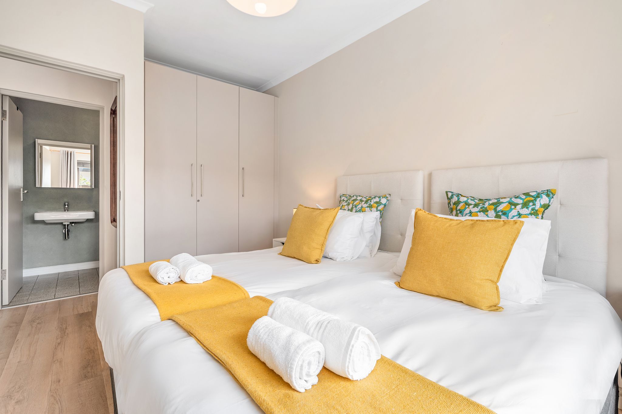A hotel room with two beds, a bathroom, and a hallway.