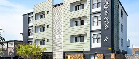 A multi-story residential building with a modern design, featuring a brick facade and a flat roof.