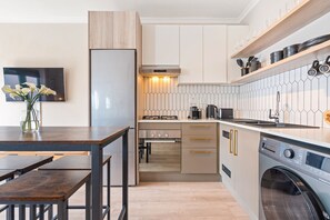 A modern kitchen with a built-in oven, a coffee machine, and a washing machine. - Beachside Condo at Cape on Viola (Cape Town)