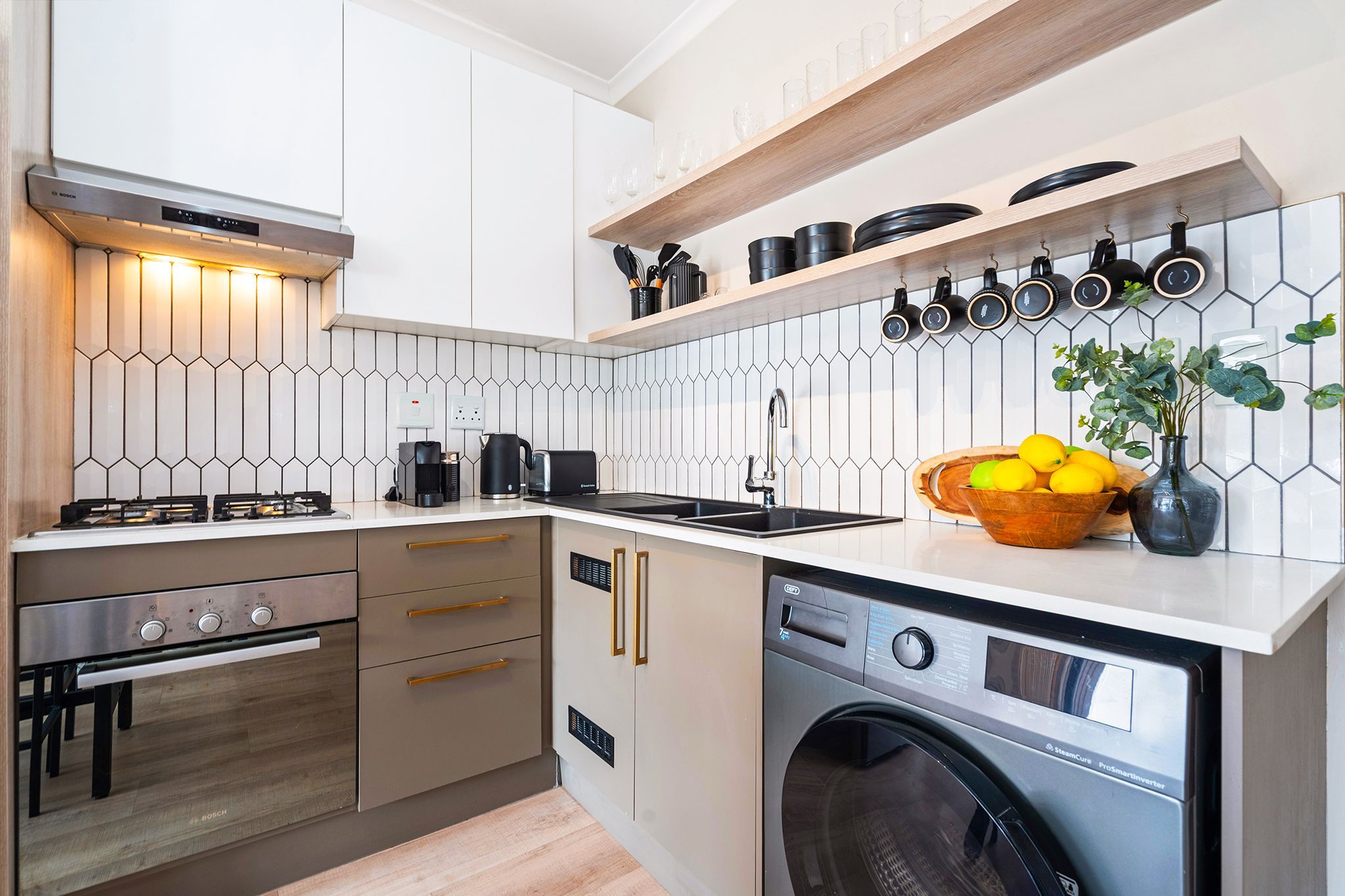 A compact kitchen with a Bosch gas stove, a built-in washing machine, and a coffee maker.