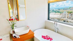 Un baño moderno con una bañera independiente, un espejo, un lavamanos y un inodoro.