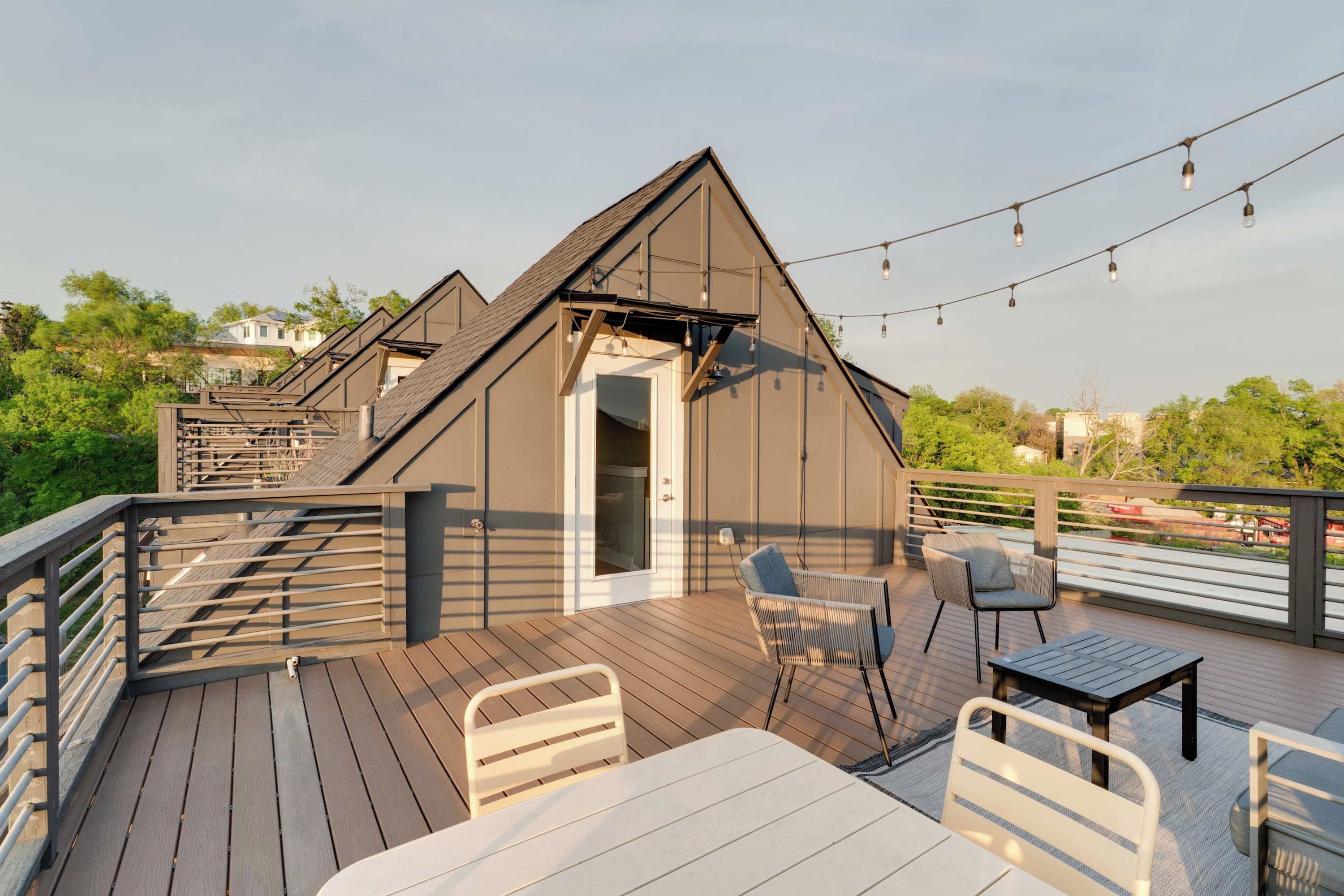 A deck with a table and chairs, a small building with a door, and string lights.