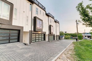 Ein mehrstöckiges Wohngebäude mit Ziegelverkleidung, großen Garagentoren und einem Flachdach.