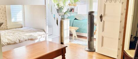 Una habitación con literas, una mesa de madera, una alfombra estampada y una silla.