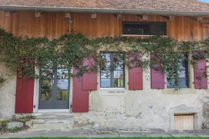 A rustic building with a wooden facade, red shutters, and a small entrance.