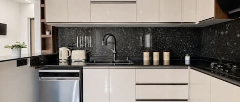 Una cocina moderna con encimera negra, electrodomésticos de acero inoxidable y salpicadero negro.