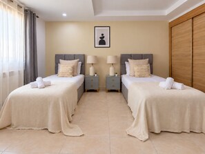 A hotel room with two beds, a nightstand with a lamp, a framed picture on the wall, and a wooden wardrobe.