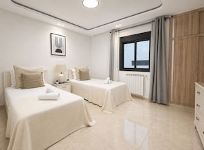 Habitación de hotel con dos camas, una ventana con cortinas, un radiador y un armario de madera.