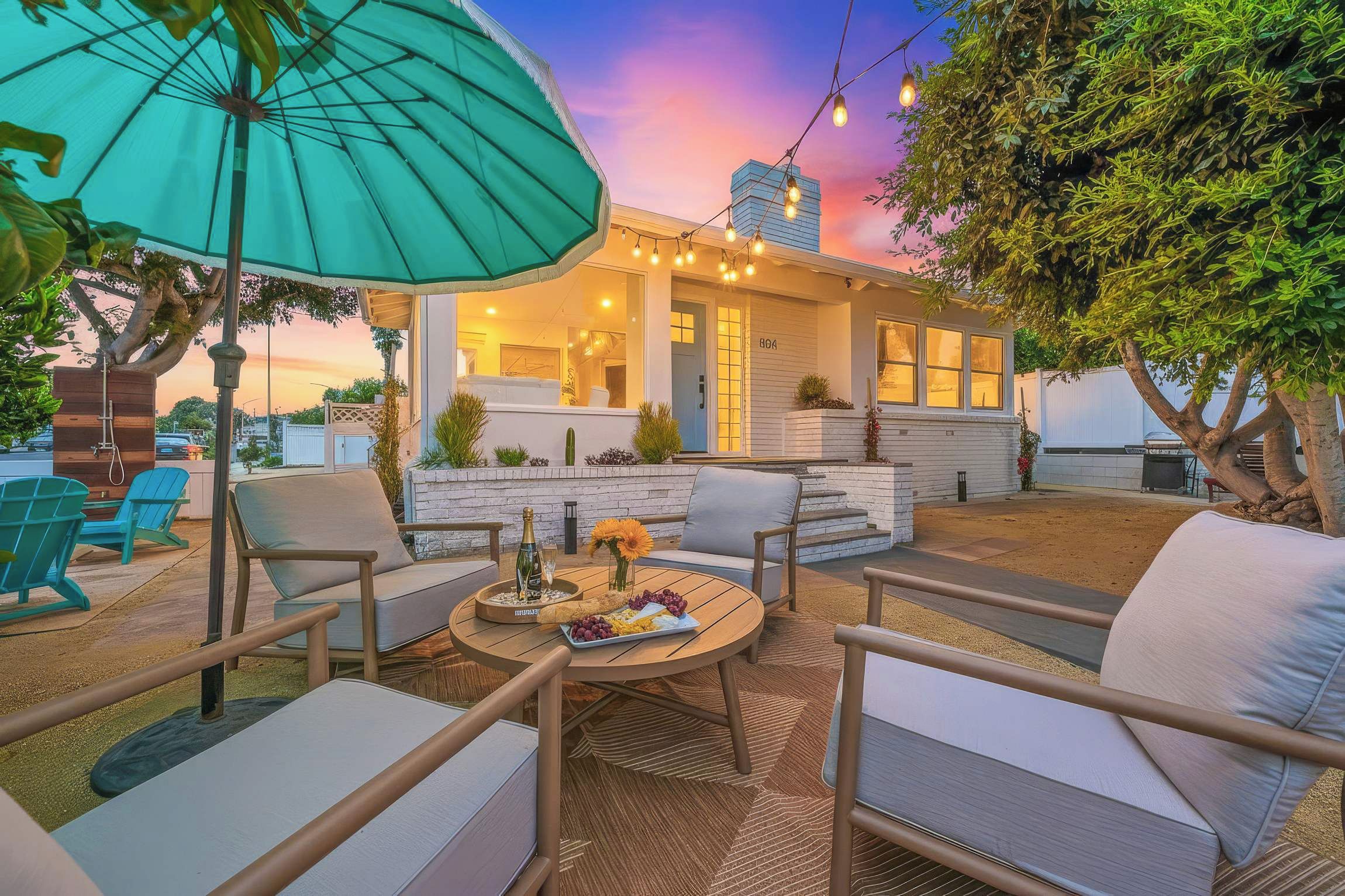 An outdoor patio area with seating, a table with a bottle and glasses, and a large umbrella.