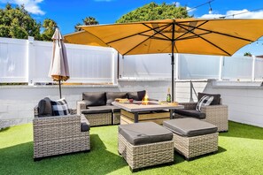 An outdoor patio with wicker furniture, a fire pit, and a large umbrella. - Tourmaline Beach Compound - Two Homes, One Getaway (San Diego)