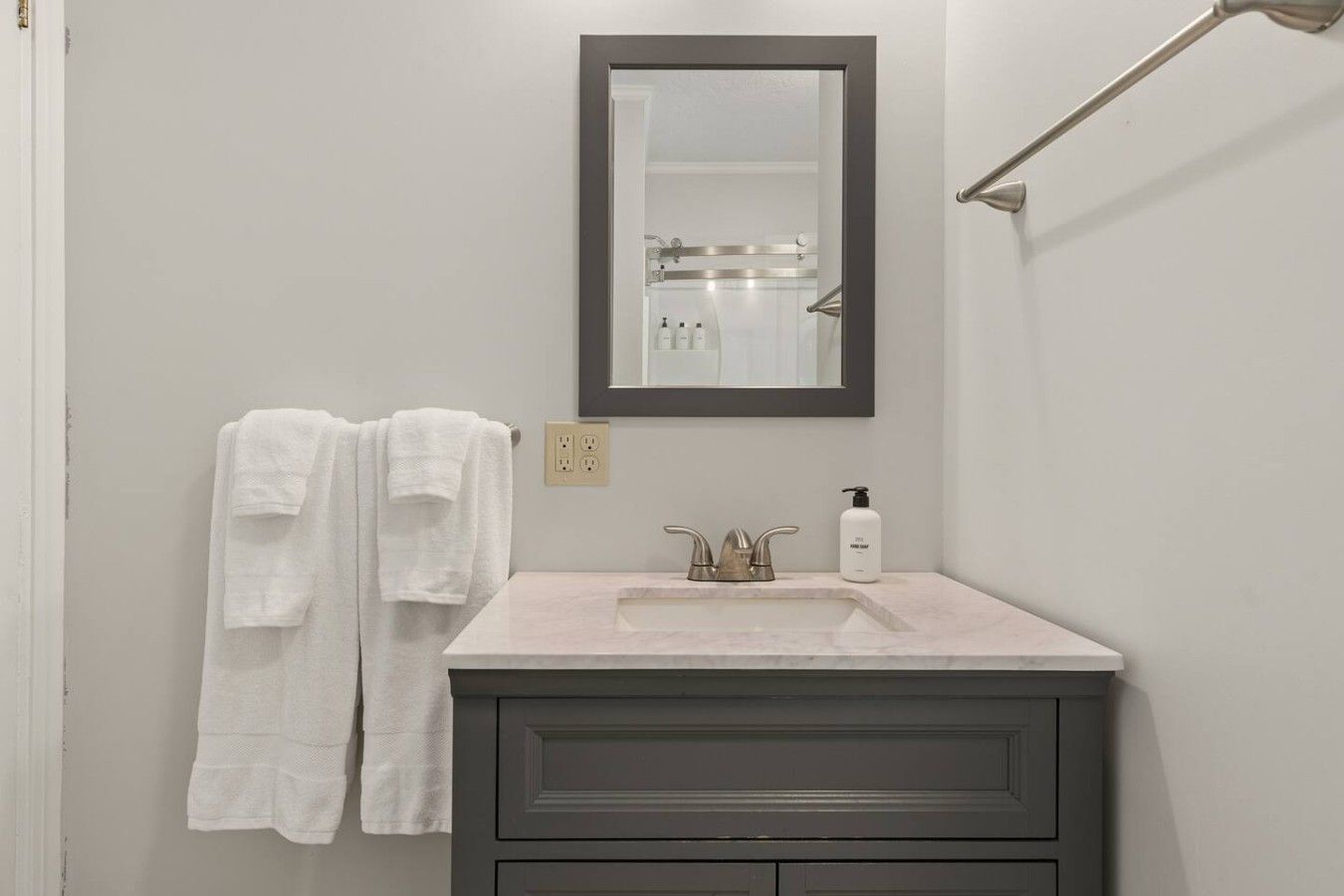 A bathroom with a white sink, a mirror, and two towels hanging on the wall.