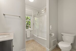 A bathroom with a bathtub, toilet, and a window. - The Federal Flat Steps From Downtown (Belfast)