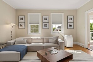 A living room with a sofa, a coffee table, a lamp, and framed pictures on the wall. - The Federal Flat Steps From Downtown (Belfast)