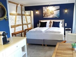 Un dormitorio con cama, mesitas de noche, cafetera y lámpara de pared.