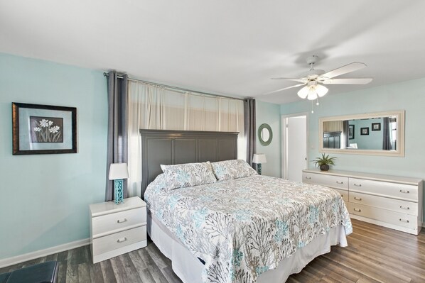 A bedroom with a bed, nightstands, a dresser, a ceiling fan, and a mirror. - Rotonda Getaway with Heated Pool & Lanai (Rotonda West)