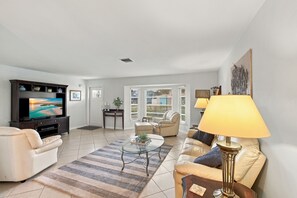 Ein Wohnzimmer mit Fernseher, Sofas, einem Couchtisch und einer Lampe.