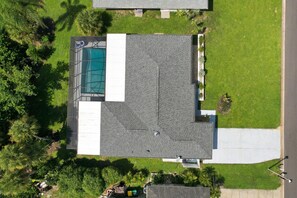 An aerial view of a residential property with a swimming pool, a covered patio, and a well-maintained lawn. - Rotonda Getaway with Heated Pool & Lanai (Rotonda West)