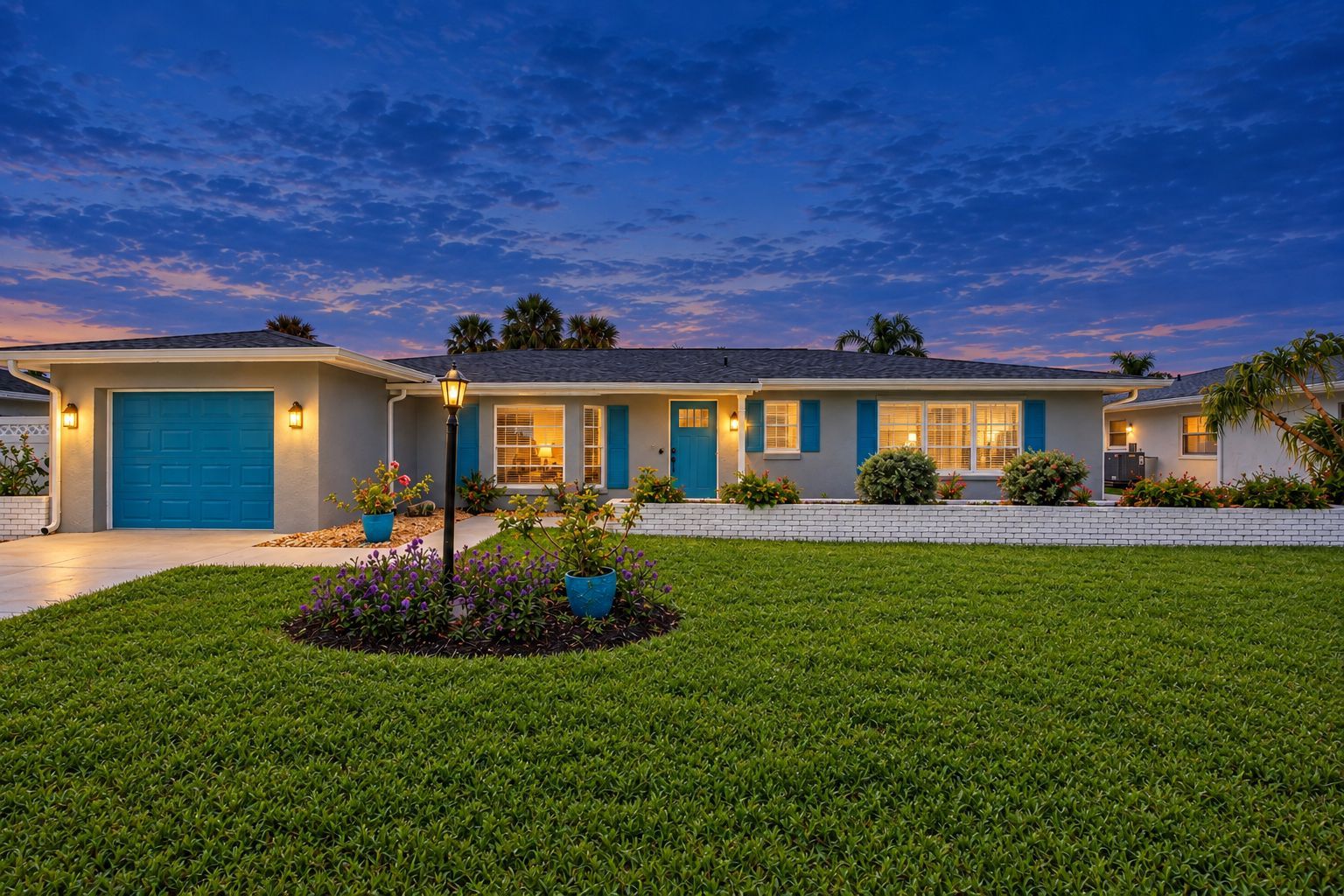 A two-story house with a blue garage door, a well-maintained lawn, and a landscaped garden with potted plants.