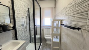 Ein modernes Badezimmer mit einer Dusche in Glasabtrennung, einer weißen Badewanne und einer Toilette.