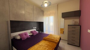 Ein Schlafzimmer mit Bett, Kommode, Spiegel und Deckenleuchte.