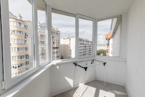 A corner room with a window overlooking a residential area, a drying rack, and a white wall.