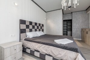 A modern bedroom with a checkered headboard, a bedside table, and a wardrobe.