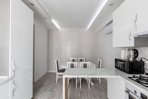 A modern kitchen with white cabinetry, a marble countertop, and a built-in microwave. - Spacious 2BR, 9th Floor View, Bright & Modern (Chișinău)