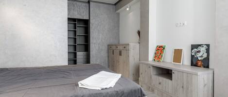 A bedroom with a bed, a wardrobe, and a vanity with a mirror.