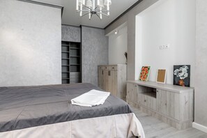 A bedroom with a bed, a wardrobe, and a vanity with a mirror. - Spacious 2BR, 9th Floor View, Bright & Modern (Chișinău)