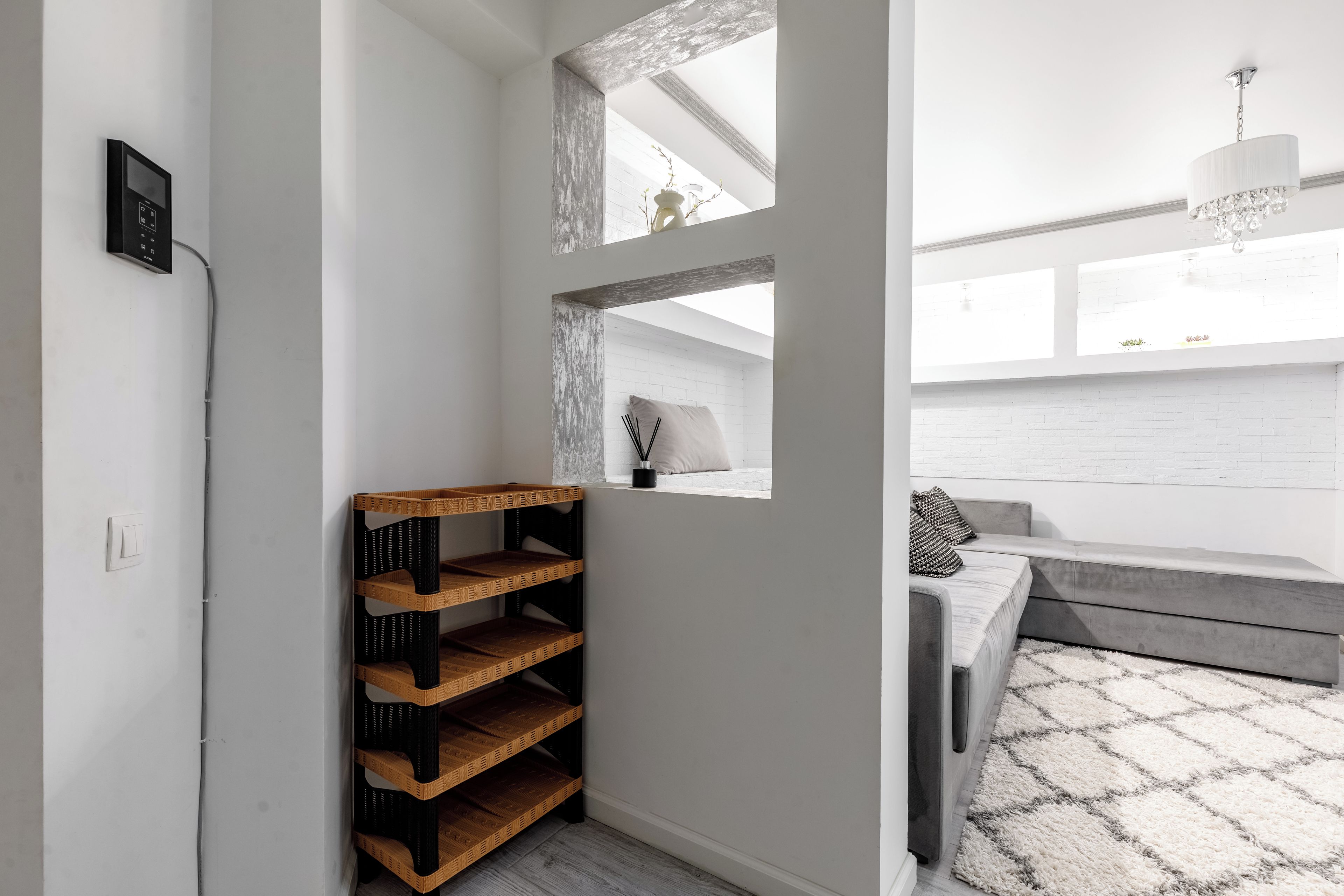 A modern interior with a built-in shelf unit, a window with a view, and a seating area with a patterned rug.