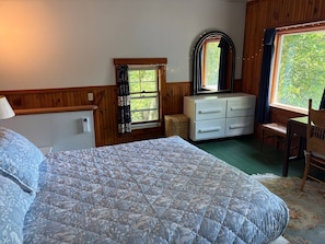 Een slaapkamer met een bed, een kaptafel en een raam met gordijnen.