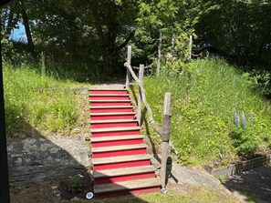 Een houten trap met rode treden die een grashelling op leidt.