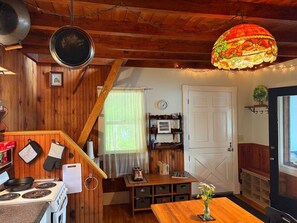 Een keuken met houten wanden, een fornuis, een spoelbak en een hangende kruidenrek.