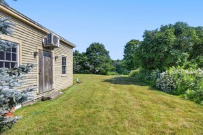 Une maison avec un jardin devant, une porte en bois et un appareil de climatisation.