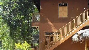 A multi-level building with a staircase, a window with shutters, and a thatched structure. - Echo Lodge (Habarana)