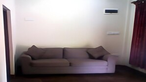 A living room with a sofa, a door, and a wall-mounted air conditioning unit. - Echo Lodge (Habarana)